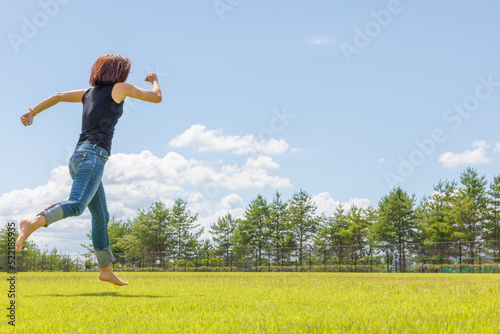 素足で芝生を走り回る女性