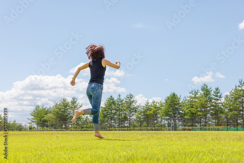 素足で芝生を走り回る女性 © M&M Factory