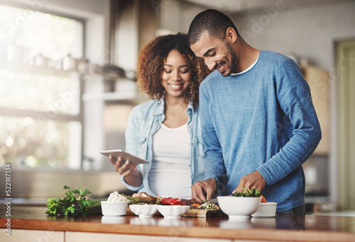 Fotografie Young, happy and romantic couple cooking healthy food together following recipes online on a tablet