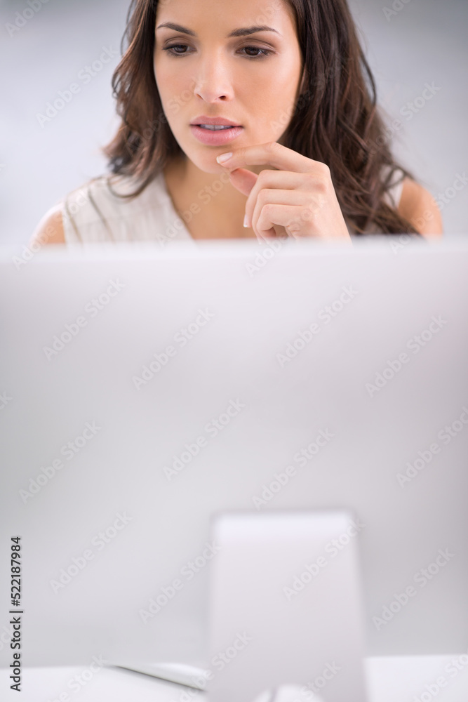 Young, serious and thinking businesswoman on a computer working on solving a business problem. Professional caucasian corporate female sitting and doing research for a company project on a modern pc Young, serious and thinking businesswoman on a computer working on solving a business problem. Professional caucasian corporate female sitting and doing research for a company project on a modern pc
