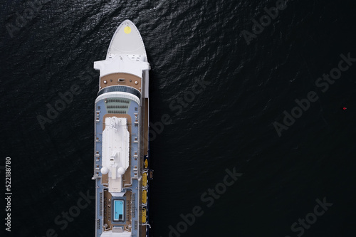 Aerial top down view on a luxury cruise ship in the ocean. Calm ocean surface. Travel and tourism concept. Luxury liner voyage. Holiday with high level of comfort. Top wooden deck and swimming pool.