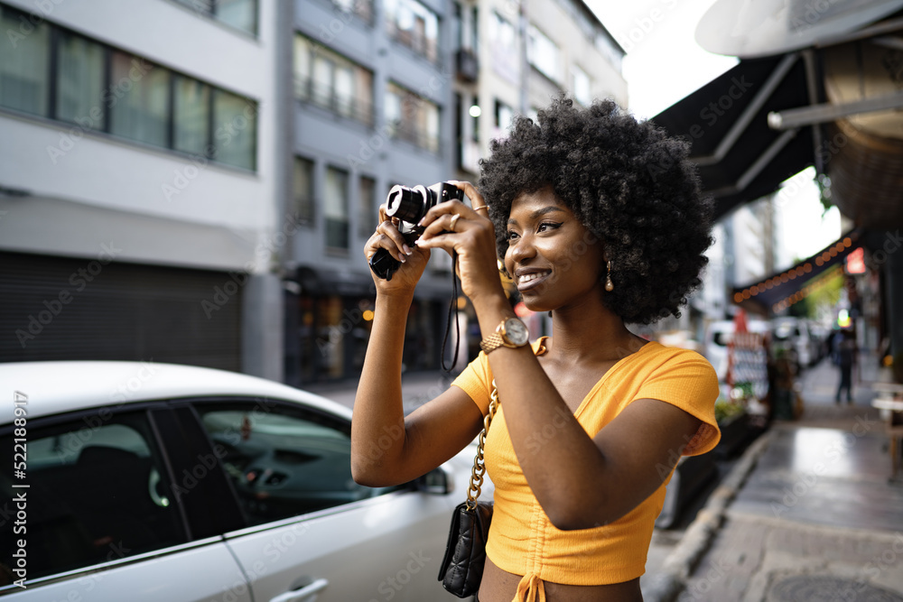 Smiling African american woman using professional camera at a street