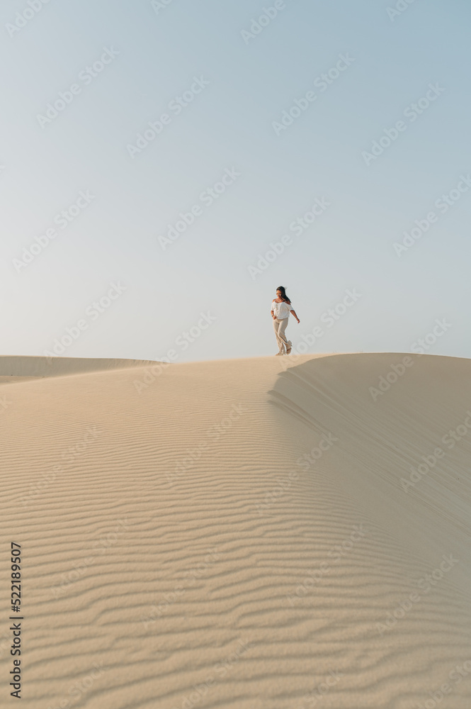 Junge Frau läuft über Sand Dünen vor blauen Himmel vertikal auf Fuerteventura Kanaren