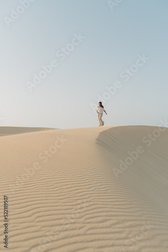 Junge Frau läuft über Sand Dünen vor blauen Himmel vertikal auf Fuerteventura Kanaren