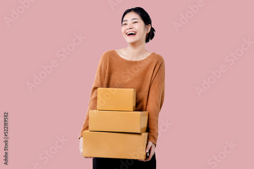 Happy Asian woman holding parcel box isolated over pink background. © RedcupStudio