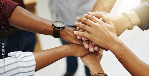 Diverse people stacking or piling hands in teamwork, success and support to show solidarity, trust and unity in office. Closeup of business team, men and women standing together and feeling motivated photo