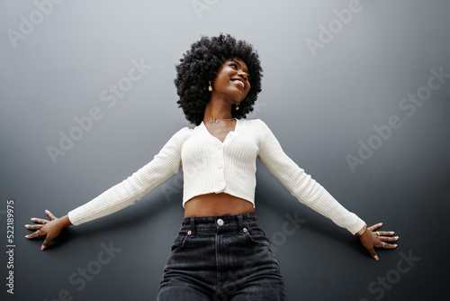 Fashionable young beautiful woman with afro hairstyle posing on the black wall