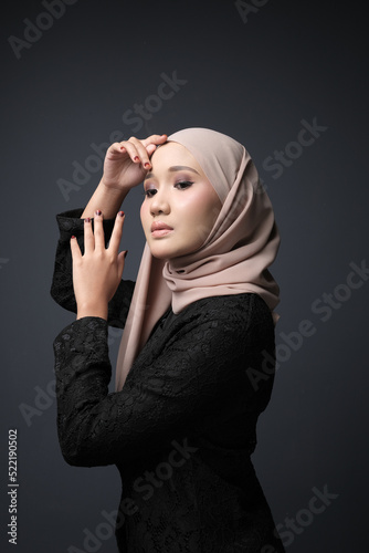 Portrait of a female  wearing a hijab, a form of lifestyle garments for Muslim women, isolated on a dark background. Eid festive and hijab fashion concept