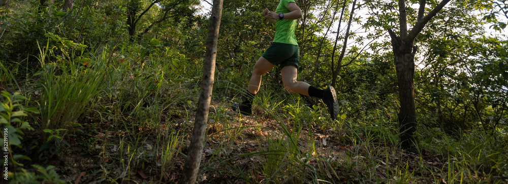 Obraz premium Woman trail runner running at sunrise tropical forest mountain peak