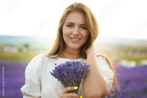 Close up portrait of a young woman holding bouquet of lavender whiile standing in lavender field
