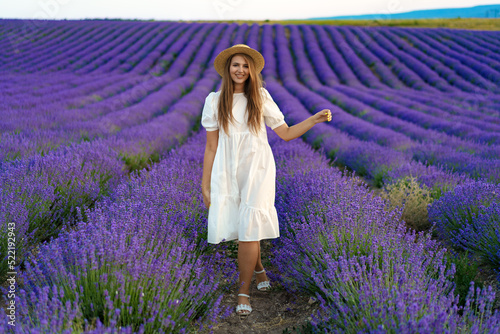 Young woman in a white dress walking in a lavender field © fotofabrika