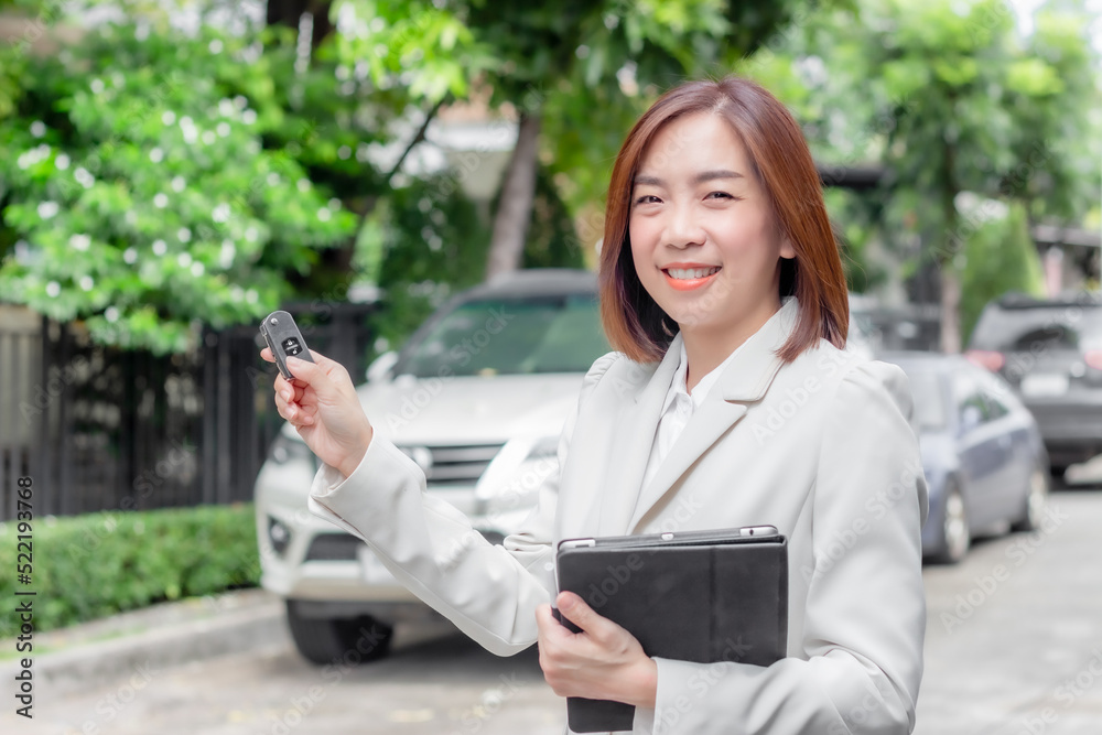 Beautiful young woman car salesman holding car keys with copy space car background Beautiful young woman car salesman holding car keys with copy space car background