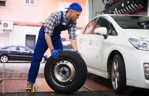 Professional american сar mechanic changing the wheel at auto repair garage