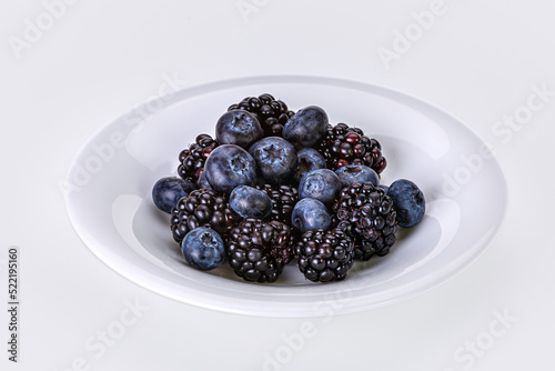 Ripe blueberries and mulberries in a white saucer