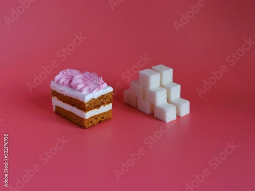 A cake and a pyramid of sugar cubes on a pink background.