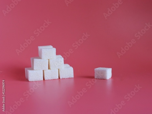 Pyramid of white sugar cubes on a pink background