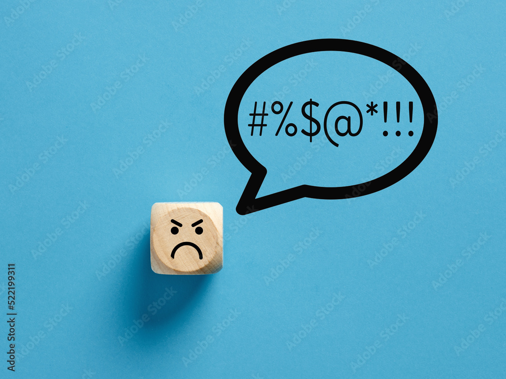 Angry face icon on a wooden cube with swearing or swearwords icons in a speech bubble. - obrazy, fototapety, plakaty 