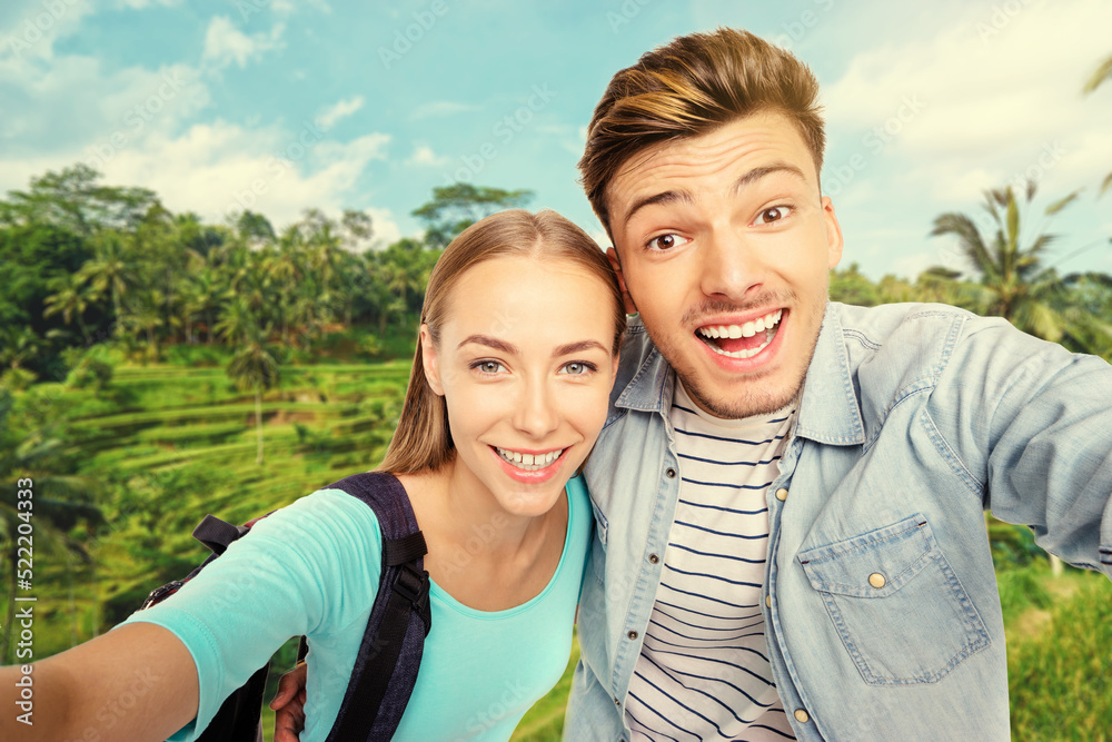 Traveling couple taking selfie against famous rice terraces near Tegallalang village, Ubud, Bali, Indonesia. Traveling couple taking selfie against famous rice terraces near Tegallalang village, Ubud, Bali, Indonesia.