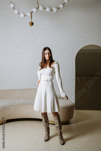 a girl in a white dress with high boots on a green background
