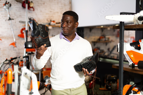 African-american man choosing boots in gardening tools store.
