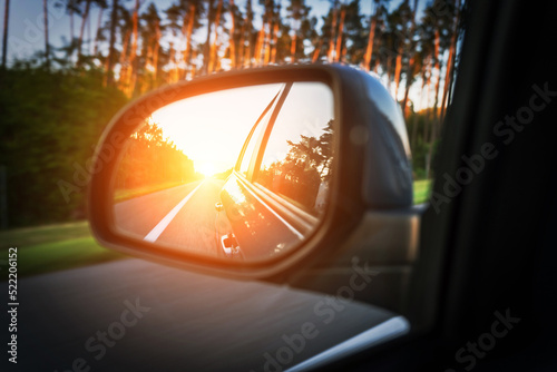 Road trip car mirror. Sun, highway car road reflection in mirror. Summer holidays trip concept. © Maksym