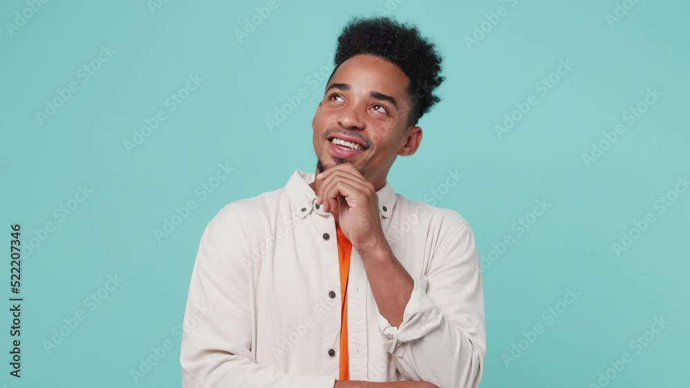 Young puzzled pensive gloomy man of African American ethnicity wear shirt t-shirt look aside put hand prop up on chin iterates over solution options isolated on plain pastel light blue cyan background Young puzzled pensive gloomy man of African American ethnicity wear shirt t-shirt look aside put hand prop up on chin iterates over solution options isolated on plain pastel light blue cyan background