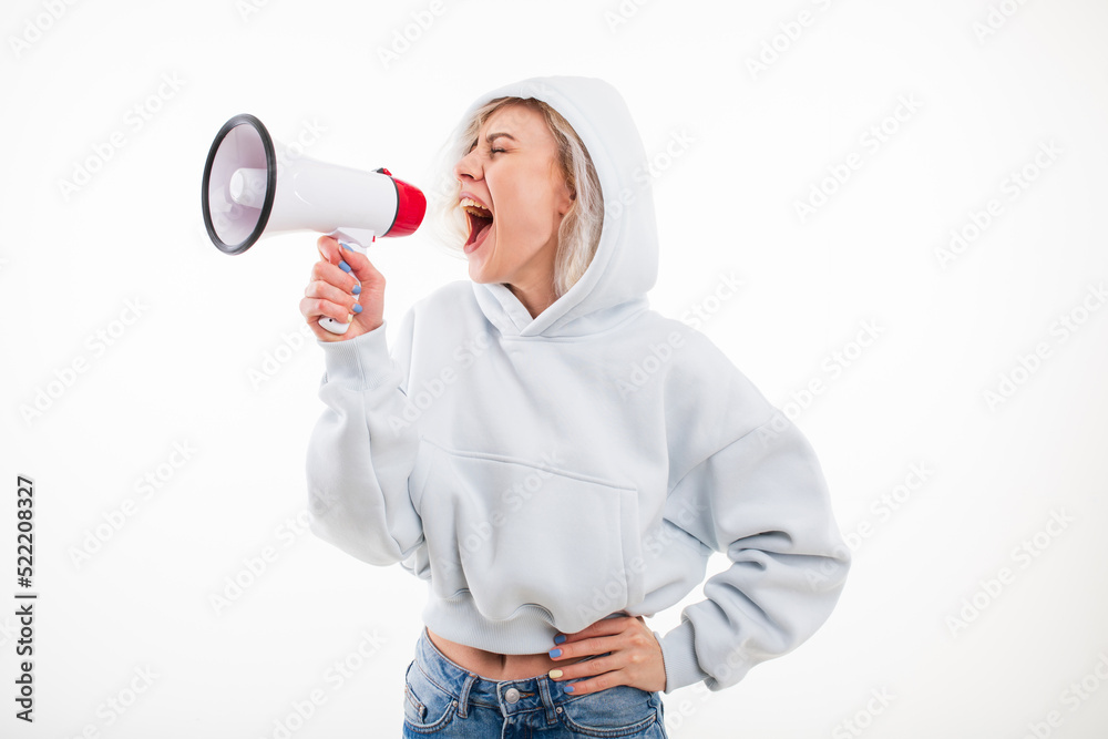 A young woman shouts into a megaphone on a white background A young woman shouts into a megaphone on a white background