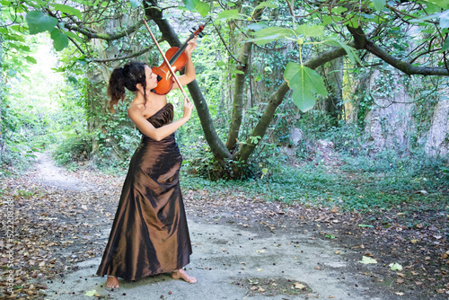 Beautiful girl playing the violin outdoors