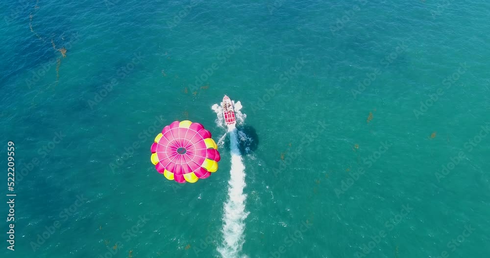 Aerial shot of a parasailing boat going over turquoise water Aerial shot of a parasailing boat going over turquoise water