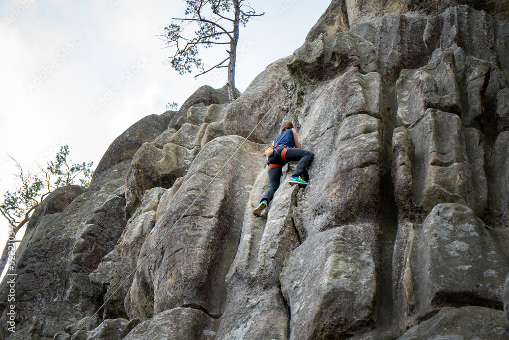 A female rock climber climbs a rock. The climber trains on natural terrain. A woman trains strength and endurance.  Active lifestyle. Extreme sports. Rock climbing in Carpath.