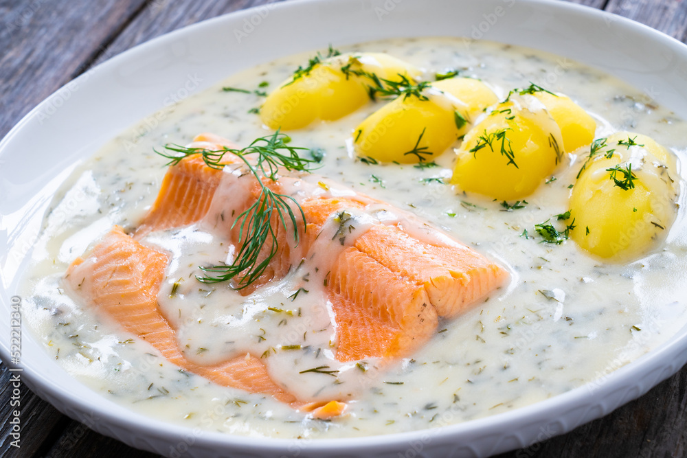 Roasted trout fillet with potatoes and dill sauce served on wooden table
