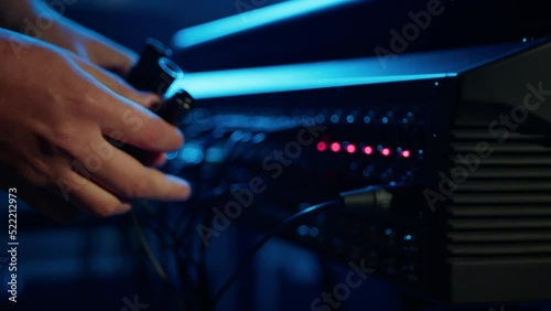 Close-up of a man plugging an XLR cable into a professional speaker. Setting up the equipment before the concert