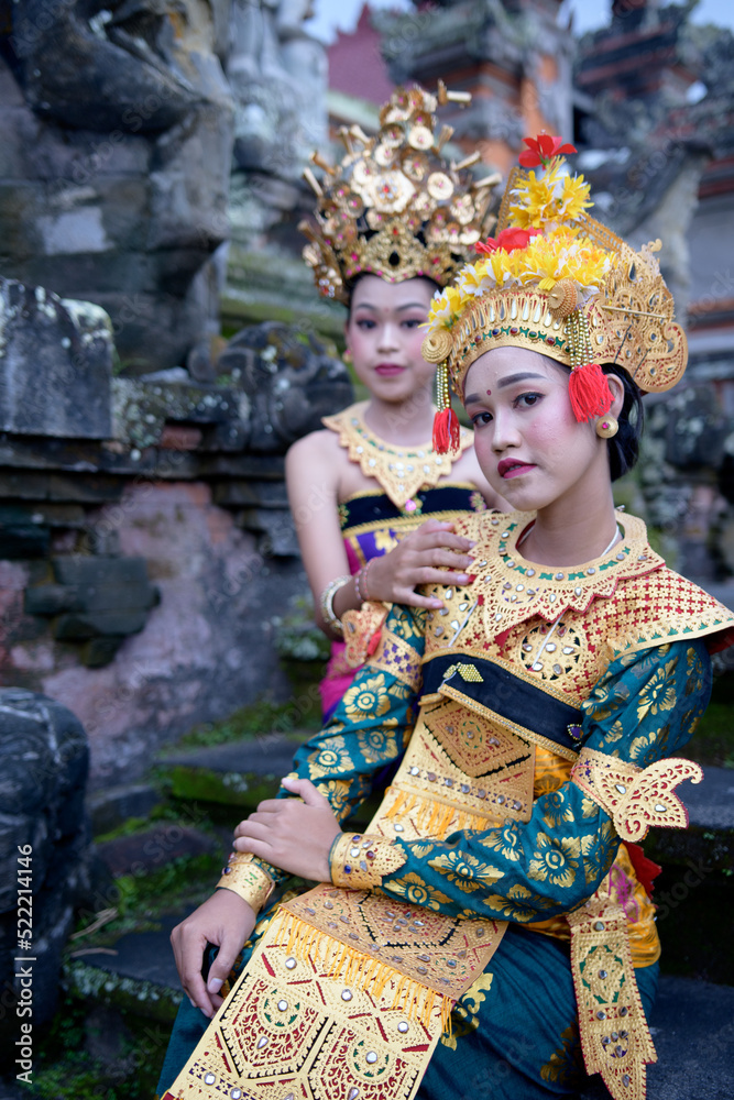 Two young Bali smiling girls make -up dressed in traditional colored costumes inside in the temple. Two young Bali smiling girls make -up dressed in traditional colored costumes inside in the temple.