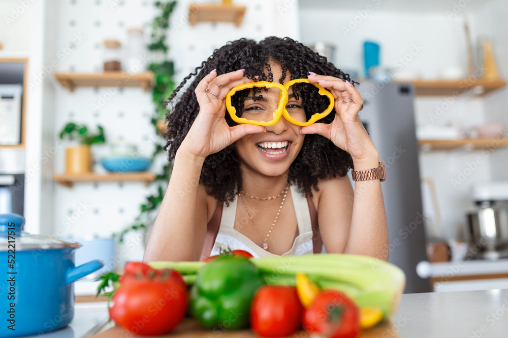 Photo of young woman smiling while cooking salad with fresh vegetables in kitchen interior at home Photo of young woman smiling while cooking salad with fresh vegetables in kitchen interior at home
