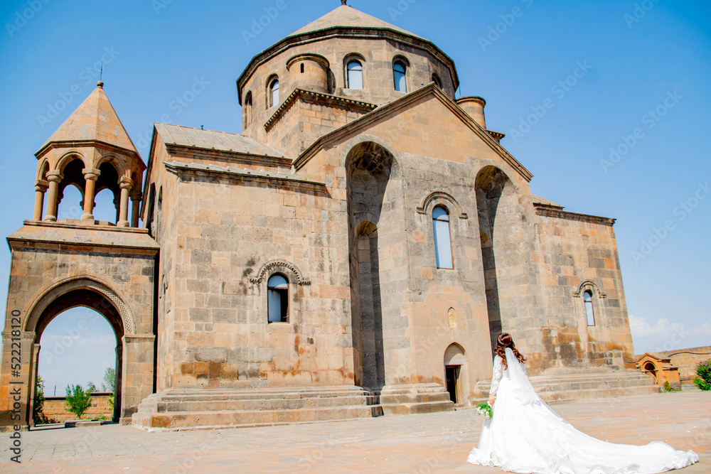 Fototapeta premium Bride in a white dress at the church. Wedding photo at the church. Bride and Church. Wedding bouquet in the hands of the bride