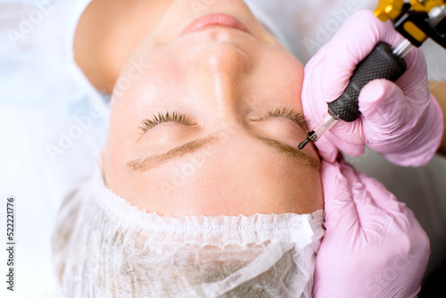 Image of a young beautiful woman dressed as a patient, lying on a couch in a cosmetology clinic.