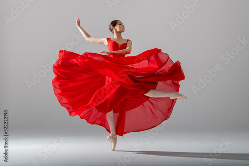 A young graceful ballerina, dressed in pointe shoes and a weightless red skirt, demonstrates her dancing skills. The beauty of classical ballet.