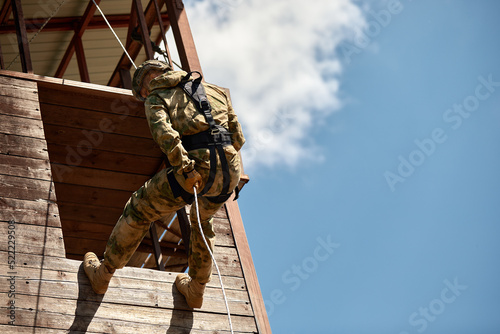 Military soldier climbing net during obstacle course in boot camp photo