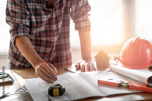 Architect & Engineer working drawing document about project planning and progress of work schedule on the home building construction site