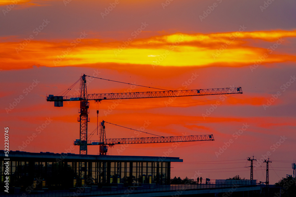construction cranes against the backdrop of the setting sun