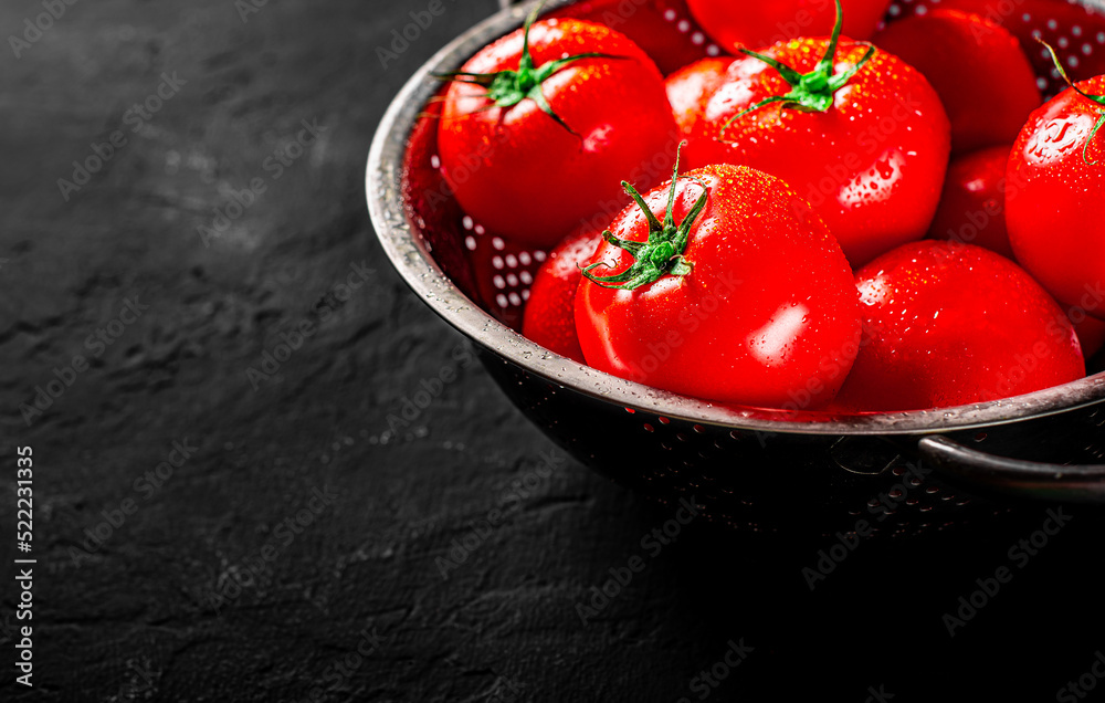 raw whole washed tomatoes in a colander on Dark grey black slate background with copy space - obrazy, fototapety, plakaty 