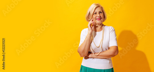Studio shot of fashionable senior woman in summer style outfit isolated on bright yellow background. Concept of beauty, emotions, vacation, travel © master1305