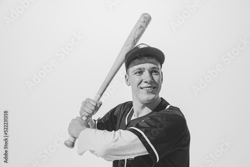 Fotografía Black and white portrait of smiling young man, baseball player in uniform with bat preparing to hit ball