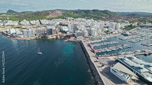 Beautiful yachts, vessels and boats by the Port Sant Antoni de Portmany in Ibiza. Aerial view of a busy Port on the Balearic Islands in Spain with beautiful mountains and city background. photo