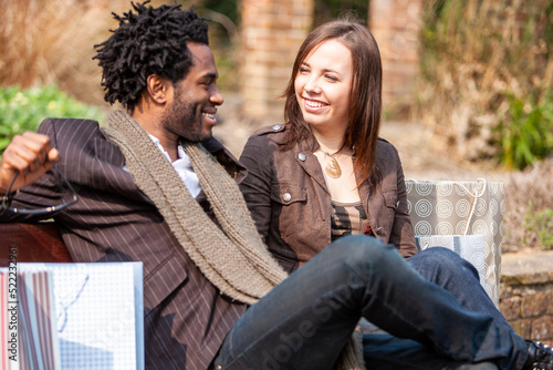 London shoppers; love and laughter. A young mixed race couple relaxing in a park after a busy day shopping. From a series of images. photo