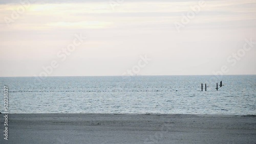 wide shot over a deserted sandy beach and the sea with buoys demarcating a swimming area photo