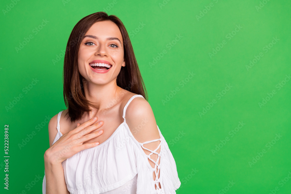 Photo of astonished satisfied person arm touch chest beaming smile empty space isolated on green color background Photo of astonished satisfied person arm touch chest beaming smile empty space isolated on green color background