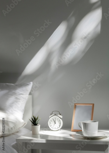 Foto a white alarm clock stands on the bedside table in the morning sun next to the m