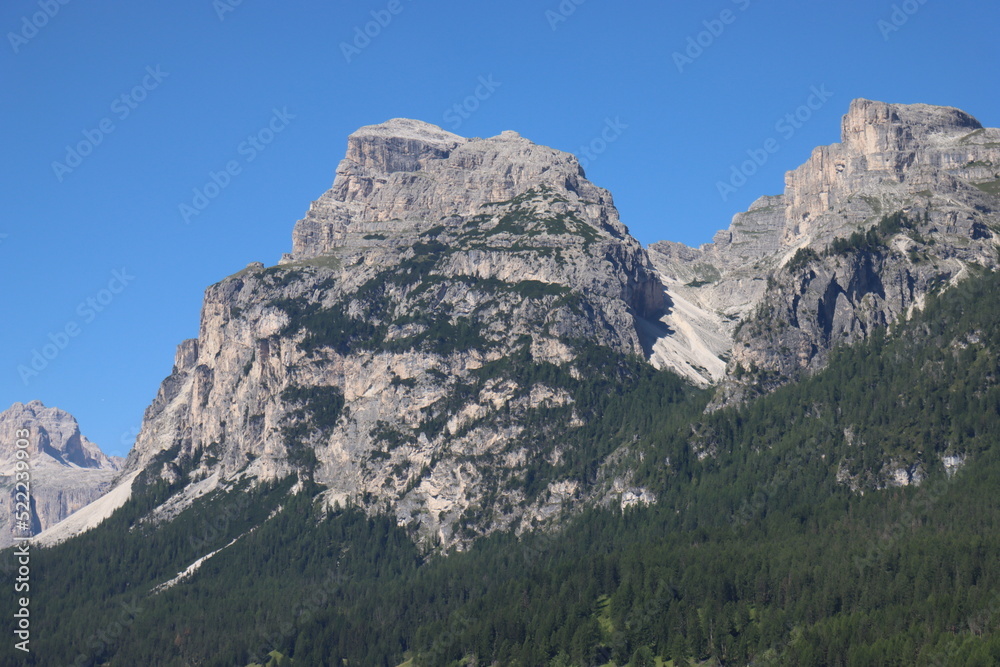 Coravara, Italy-July 16, 2022: The italian Dolomites behind the small village of Corvara in summer days with beaitiful blue sky in the background. Green nature in the middle of the rocks.