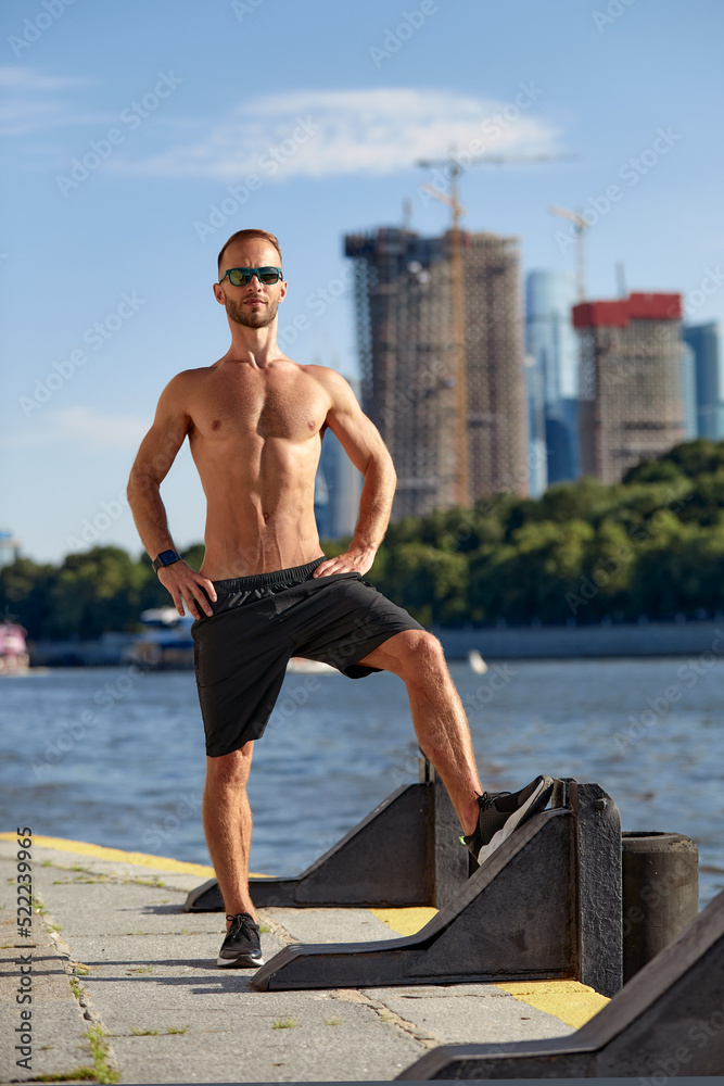 Athletic man running and doing functional workout outdoors - Sportive adult male with sportswear training in a city on the river bank